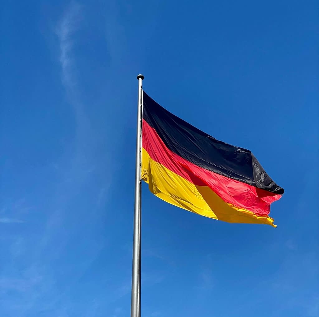 Germany German flag waving against blue sky - symbol of Germany as new world's largest creditor after surpassing Japan