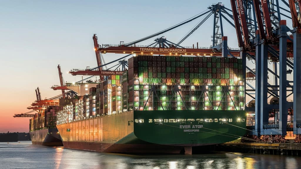 Shipping goods Large container ships at international port with loading cranes during sunset - US China trade relations and global commerce