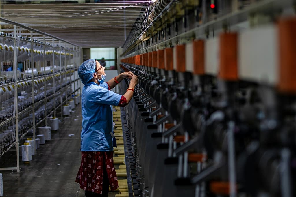 Manufacturing Chinese textile factory worker operating manufacturing equipment as part of Xi Jinping's new industrial strategy 2025